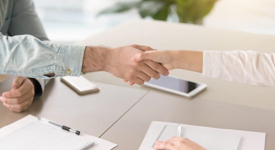 Close up side view of male and female hands shaking above the table. Greeting or congratulating gesture at the meeting, students holding debates, young partners starting a startup